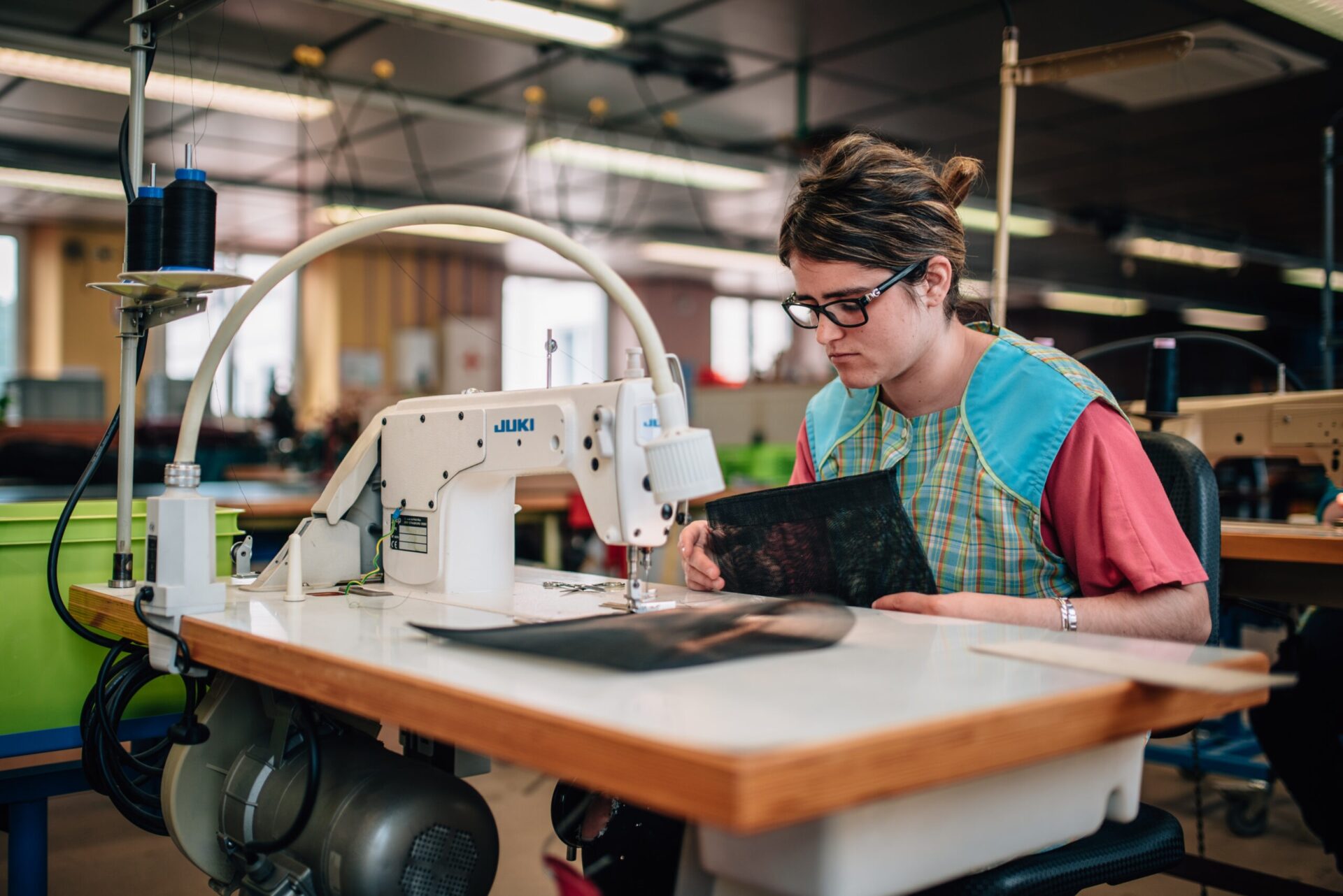 Présentation Atelier Couture : personne handicapée en train de faire de la couture sur une machine à coudre industrielle