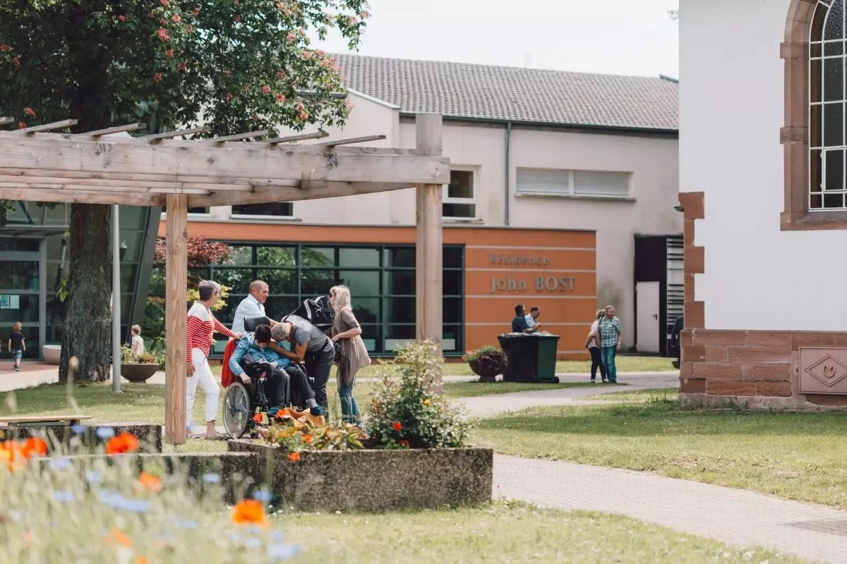 Vue extérieure de la Fondation Sonnenhof avec un groupe de personnes discutant ensemble