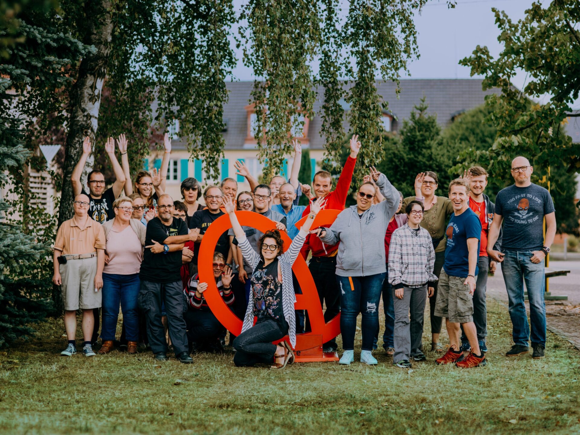 Groupes de moniteurs et travailleurs handicapés du Sonnenhof posant bras levés avec le logo Alsace